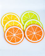 Set of six circular coasters designed to look like citrus fruits, including orange, yellow, and lime slices, arranged on a white background.
