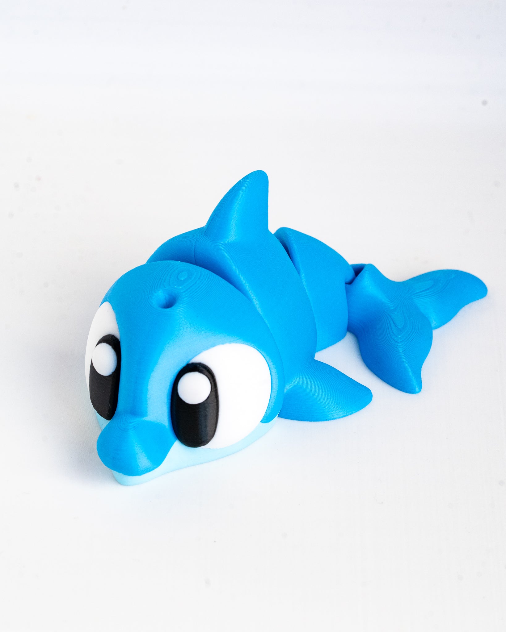 A blue dolphin-shaped bath toy with large cartoon eyes, photographed on a plain white background.