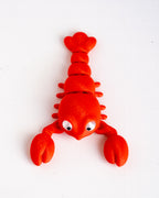 A bright red lobster-shaped toy or decoration with large white eyes, photographed on a plain white background.