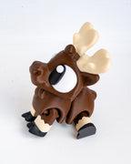 A small brown moose figurine with large cream-colored antlers, a white and black eye, and black hooves, photographed on a plain white background.