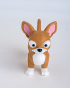 A small brown and white dog figurine with pink inner ears, photographed against a plain light gray background.