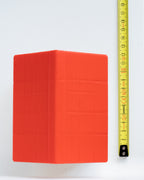 A dog house on a white background next to a yellow measuring tape for scale.