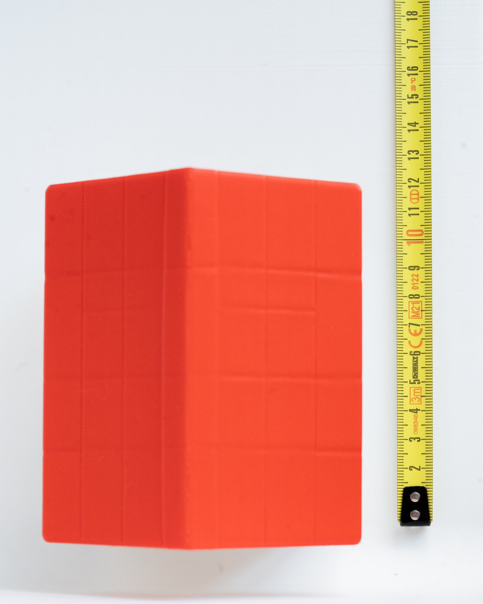 A dog house on a white background next to a yellow measuring tape for scale.