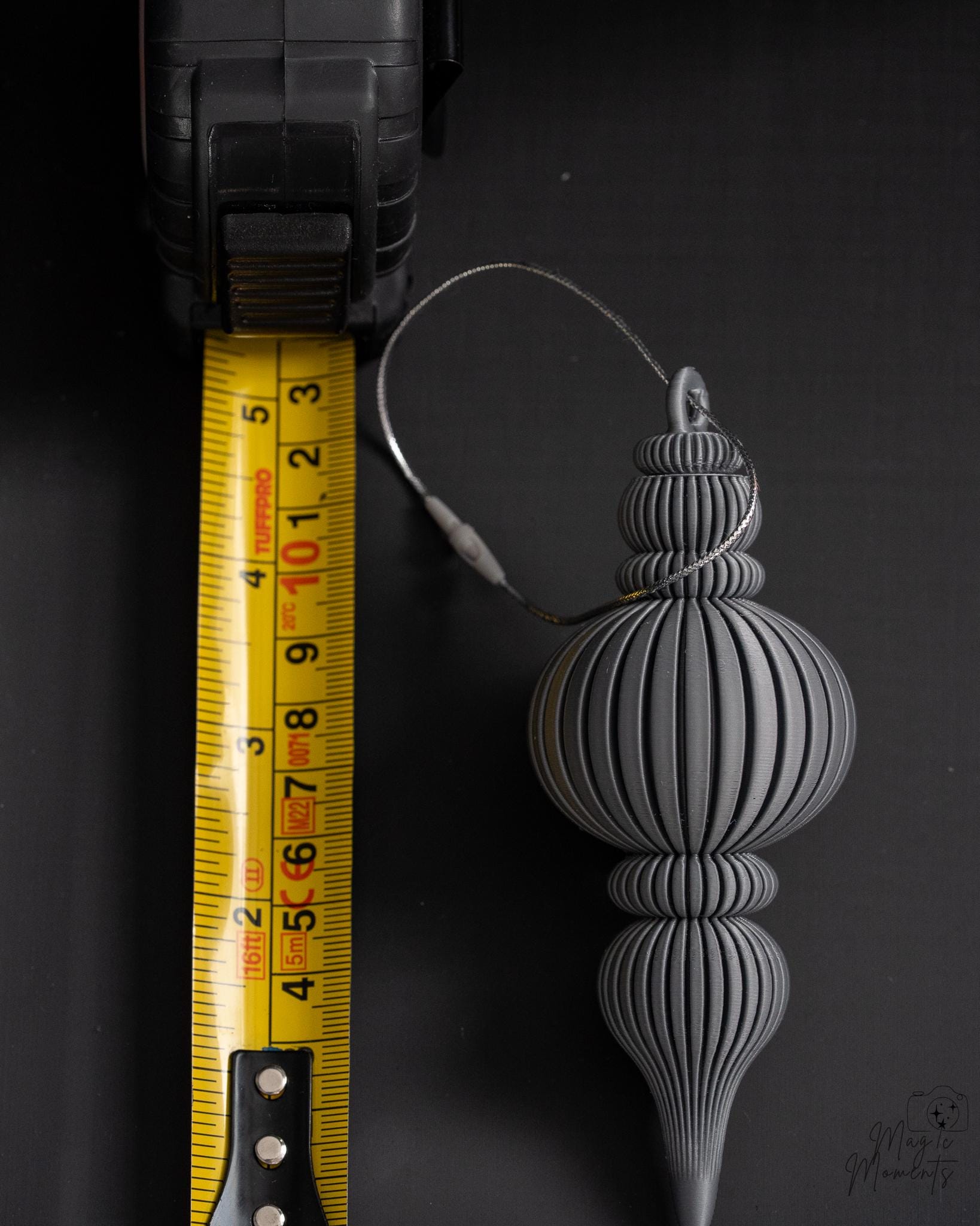 Grey Christmas ornament next to measuring tape for scale