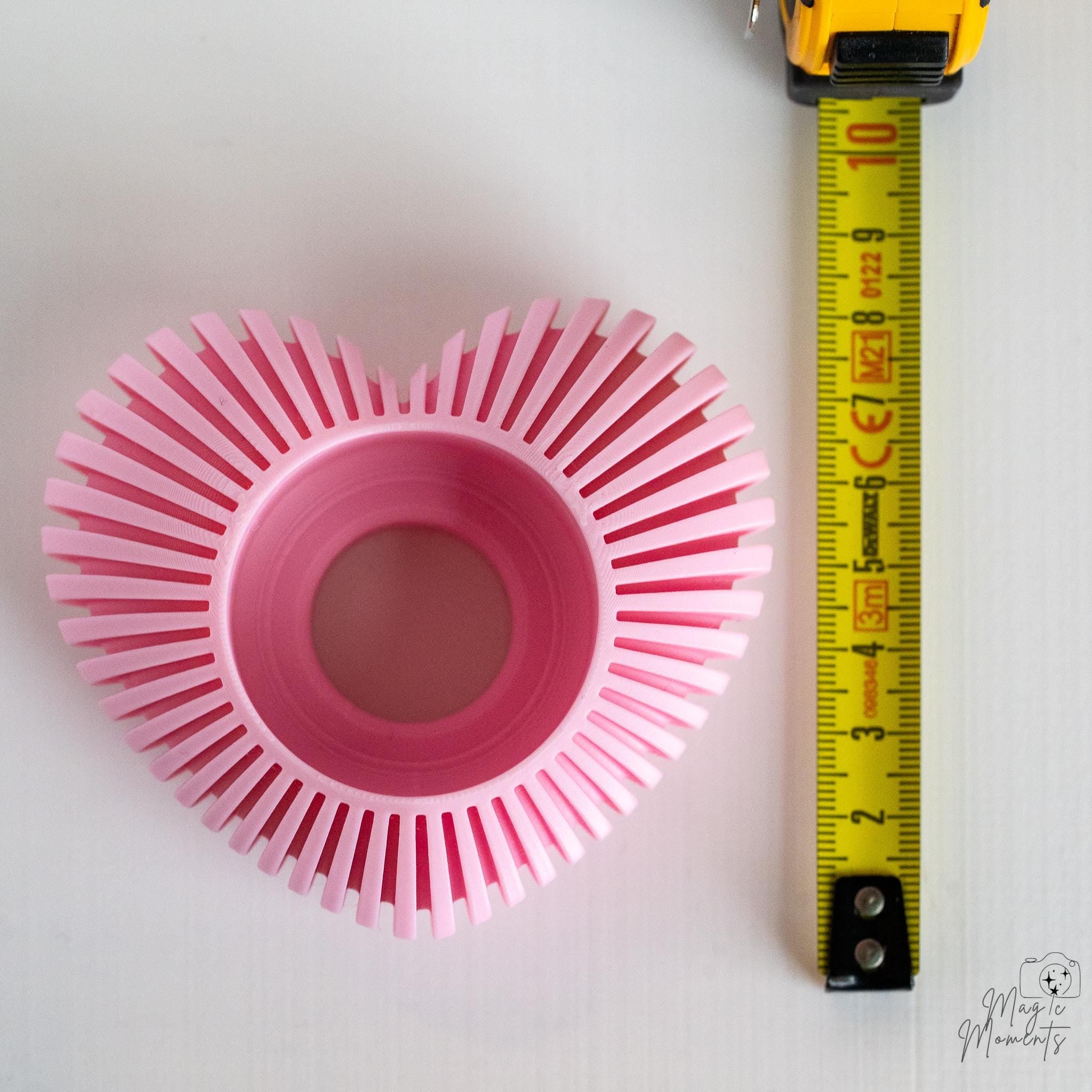Pink heart tealight holder next to measuring tape for scale