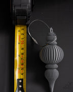 grey ribbed christmas bauble ornament next to measuring tape for scale