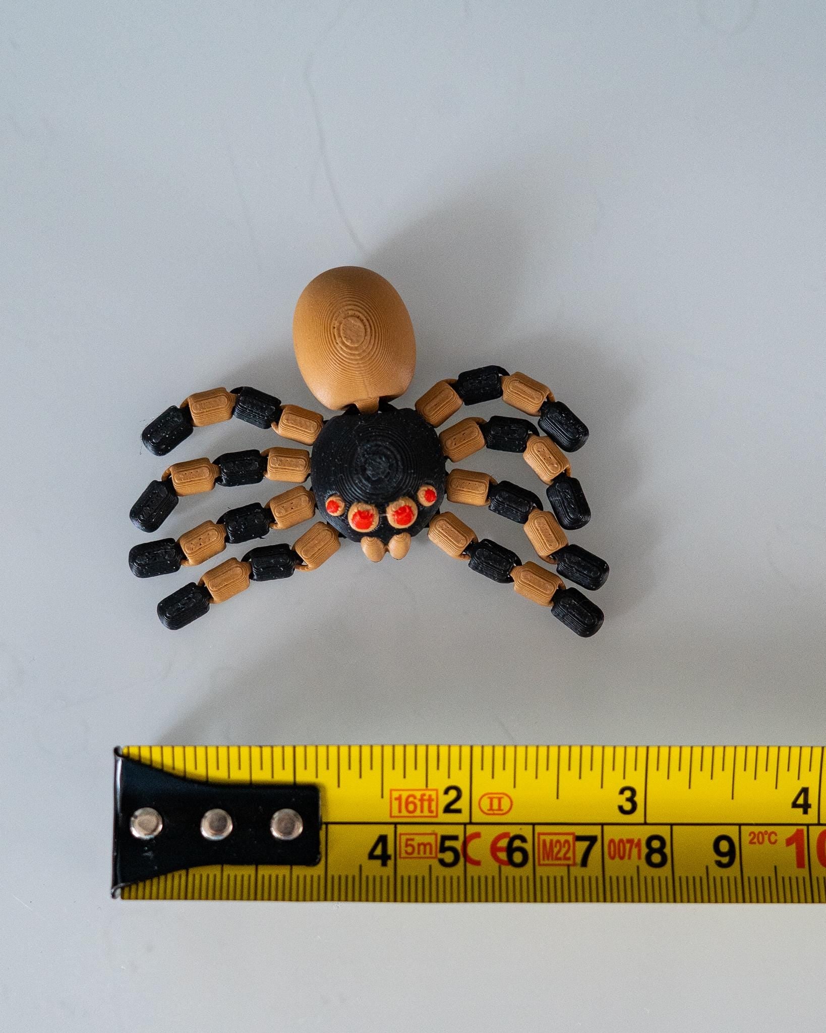 spider figurine next to measuring tape for scale