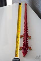Flexible articulated dragon next to measuring tape for scale