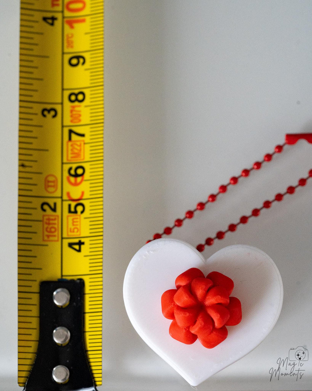 heart clicker ornament next to measuring tape for scale