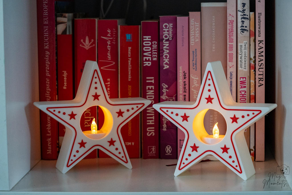 Two star-shaped candle holders with candles on a shelf with books in the background.