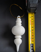 white ribbed christmas bauble ornament next to measuring tape for scale