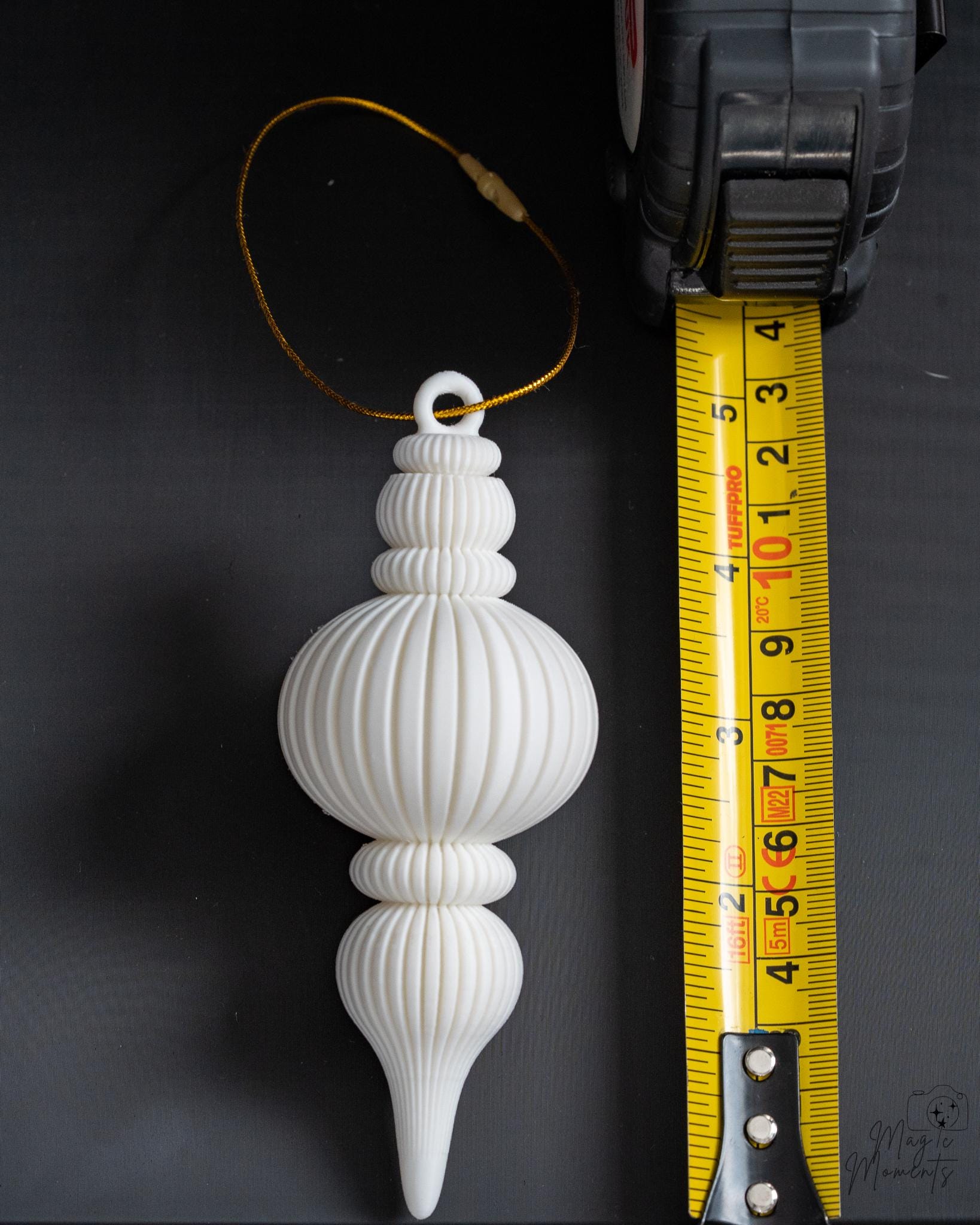 white ribbed christmas bauble ornament next to measuring tape for scale