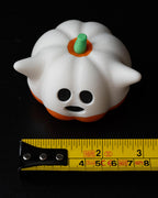 cute ghost pumpkin figurine next to measuring tape for scale