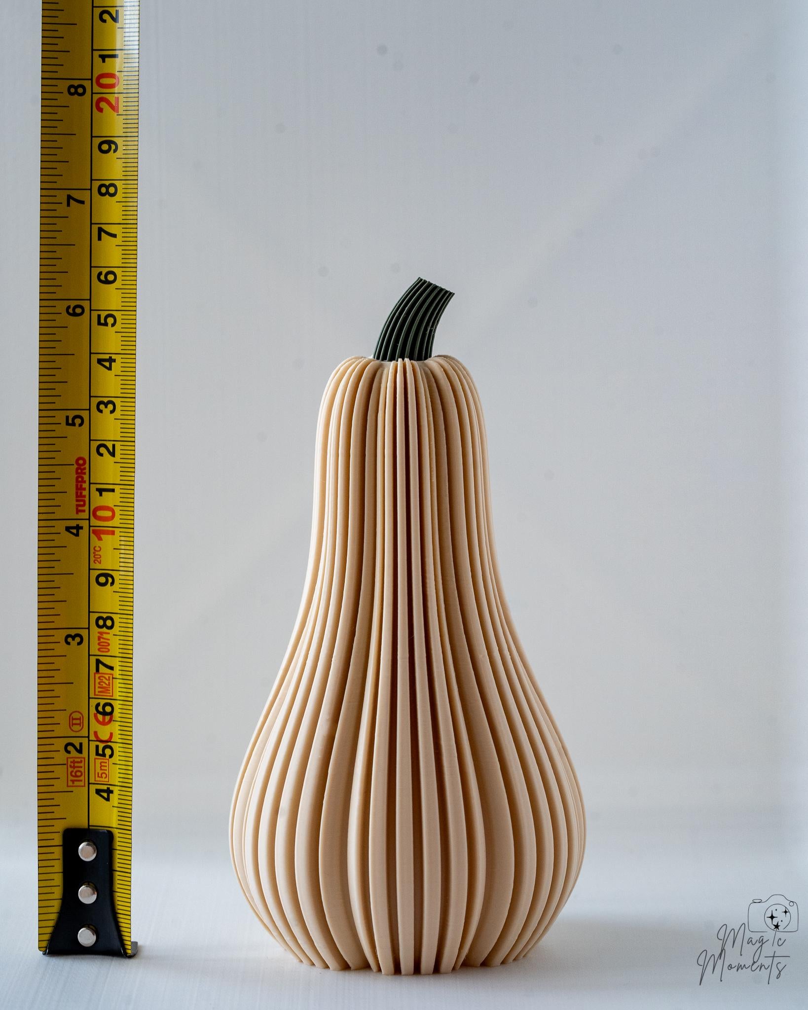 Decorative butternut squash with ribbed texture next to a measuring tape on a white background