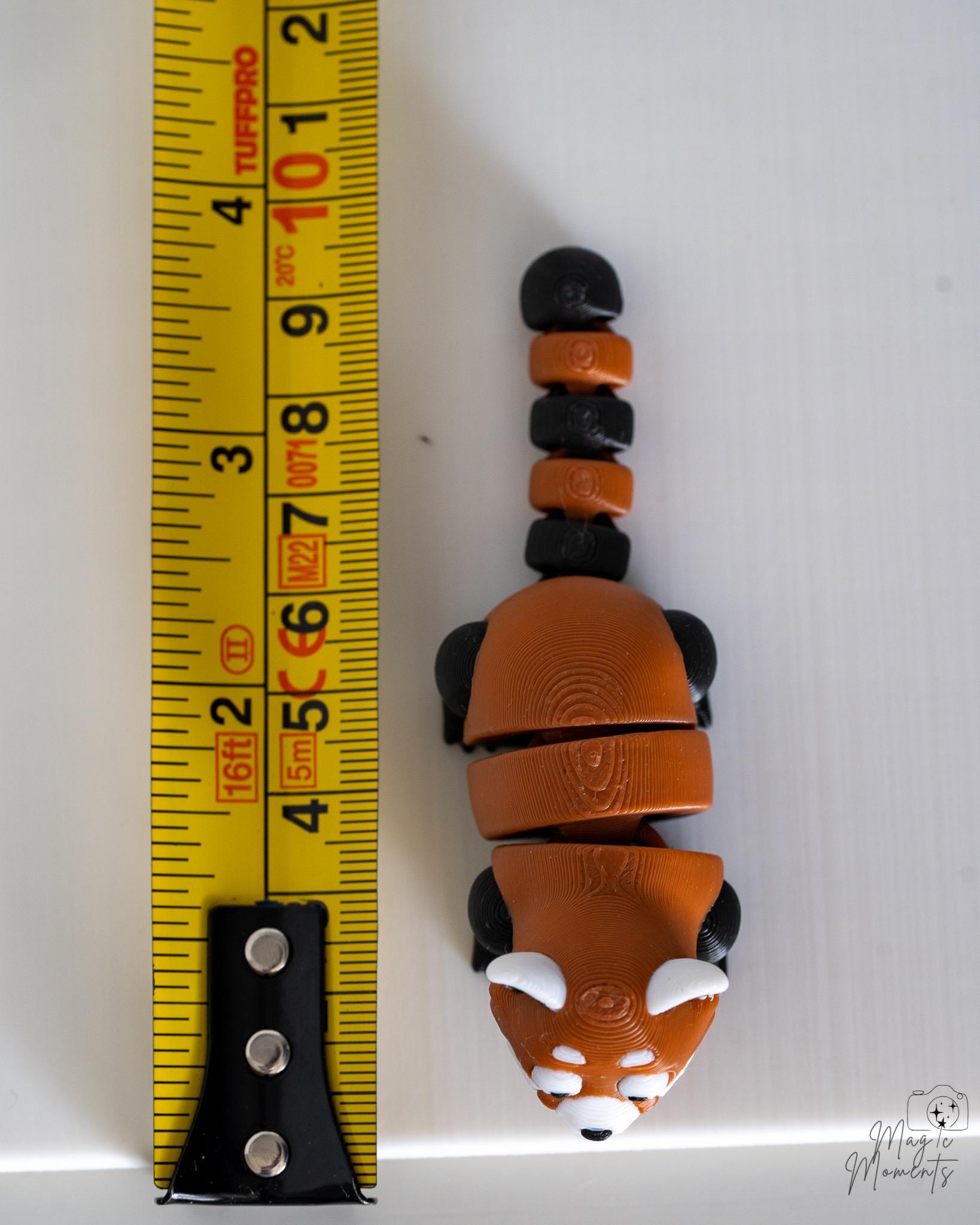 red panda figurine next to measuring tape for scale