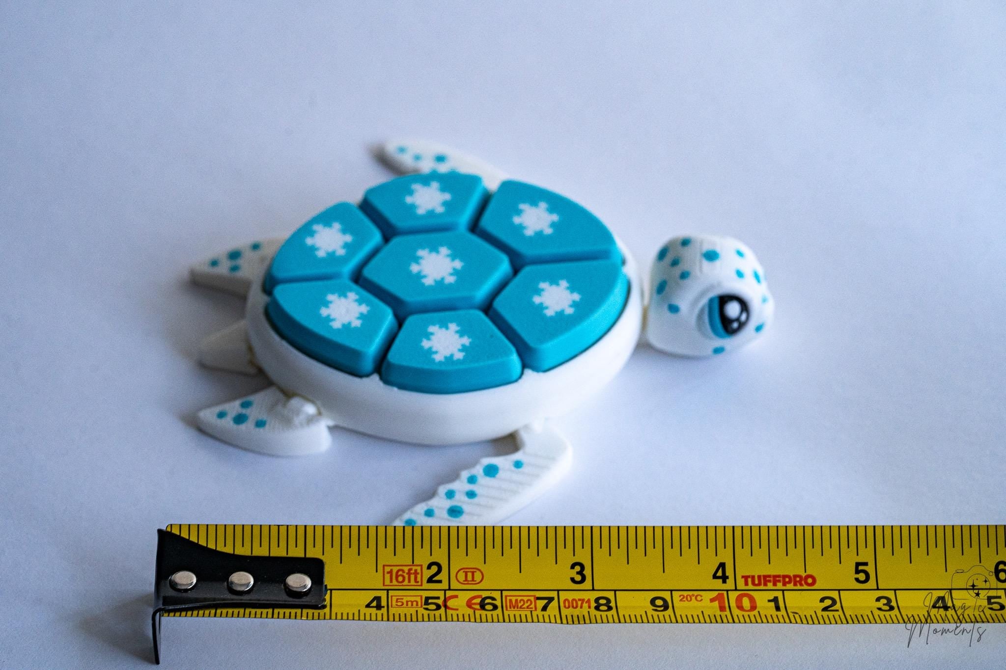 Snowflake turtle clicker next to measuring tape for scale