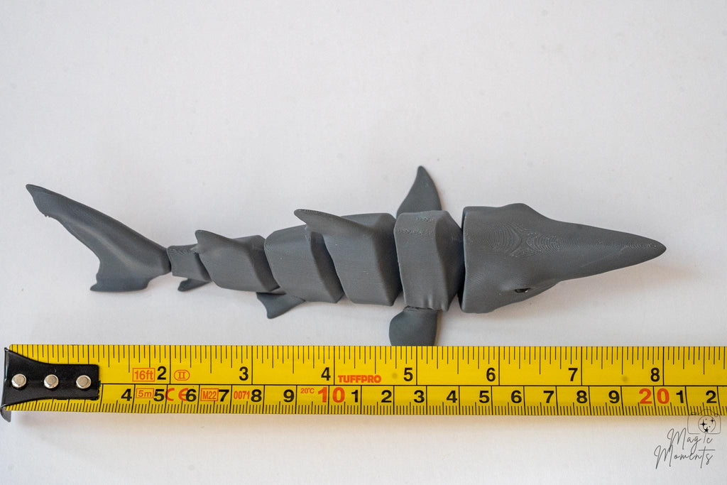 Articulated shark figure next to measuring tape for scale