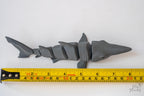 Articulated shark figure next to measuring tape for scale