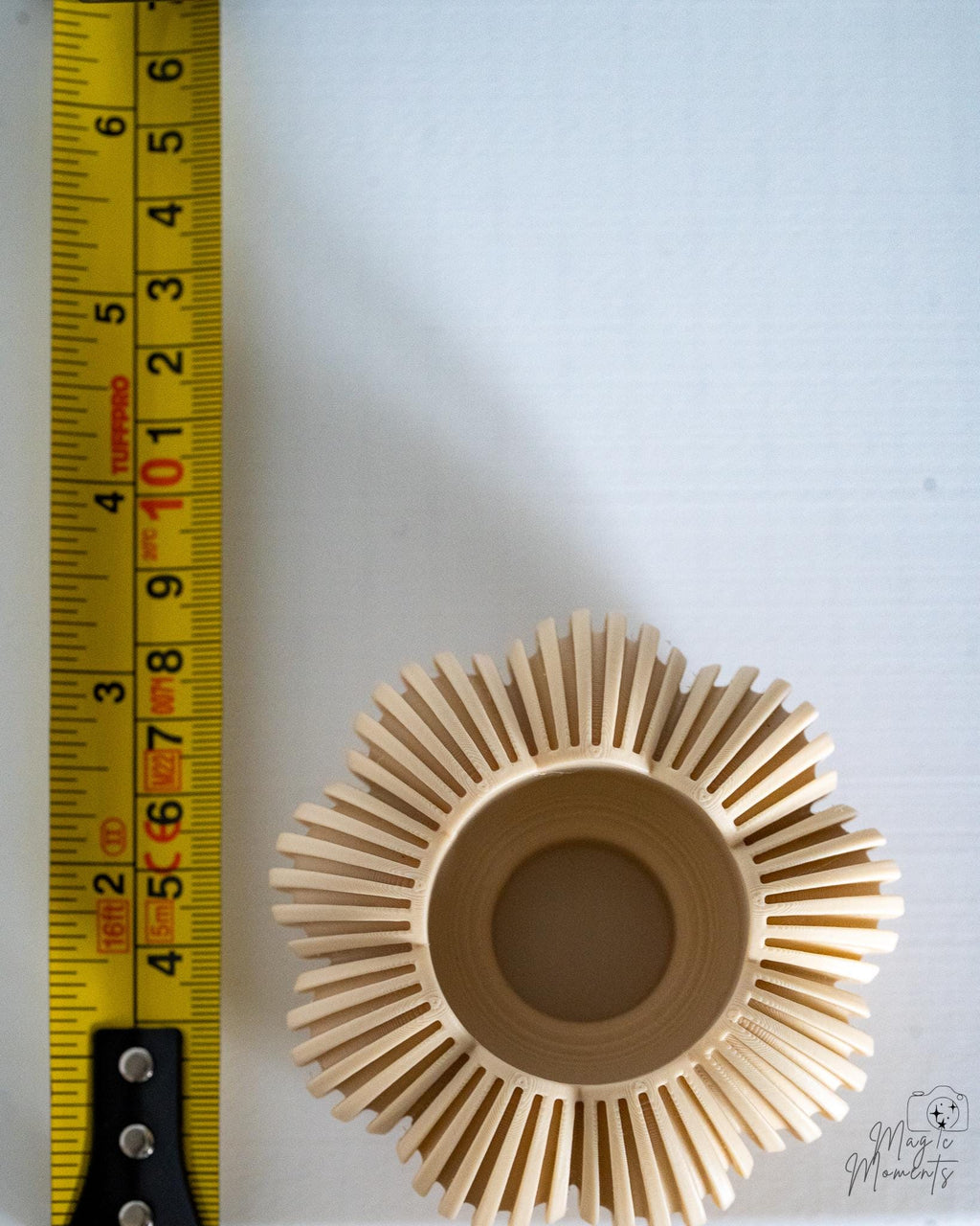 Beige pumpkin tealight holder viewed from above next to measuring tape for scale