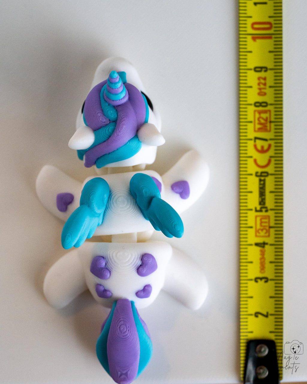 Articulated unicorn figure next to measuring tape for scale