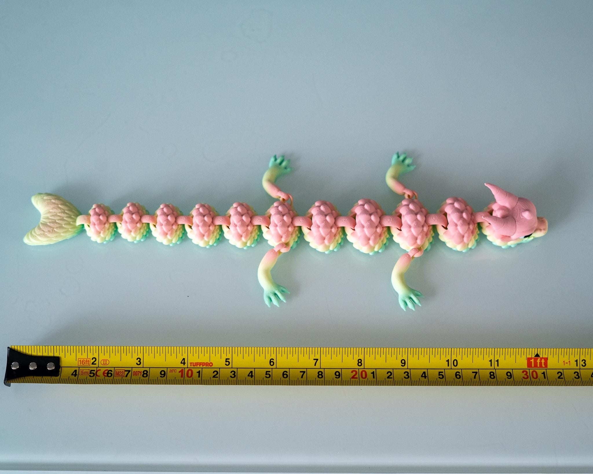 Pastel dragon display figure next to measuring tape for scale