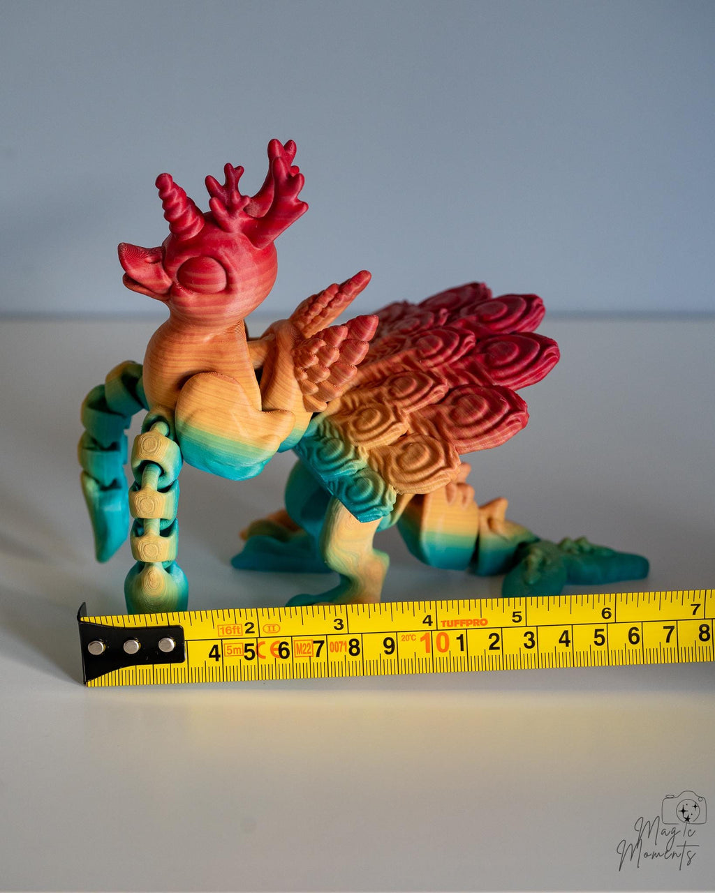 Articulated phoenix figure next to measuring tape for scale