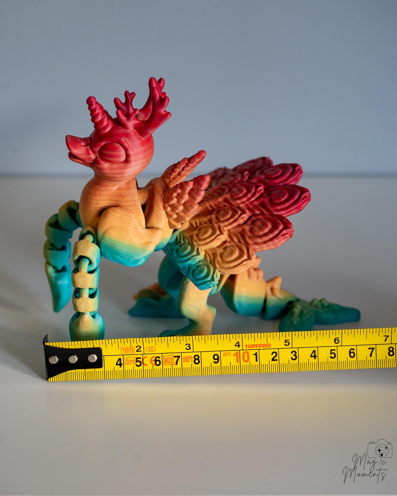 Articulated phoenix figure next to measuring tape for scale