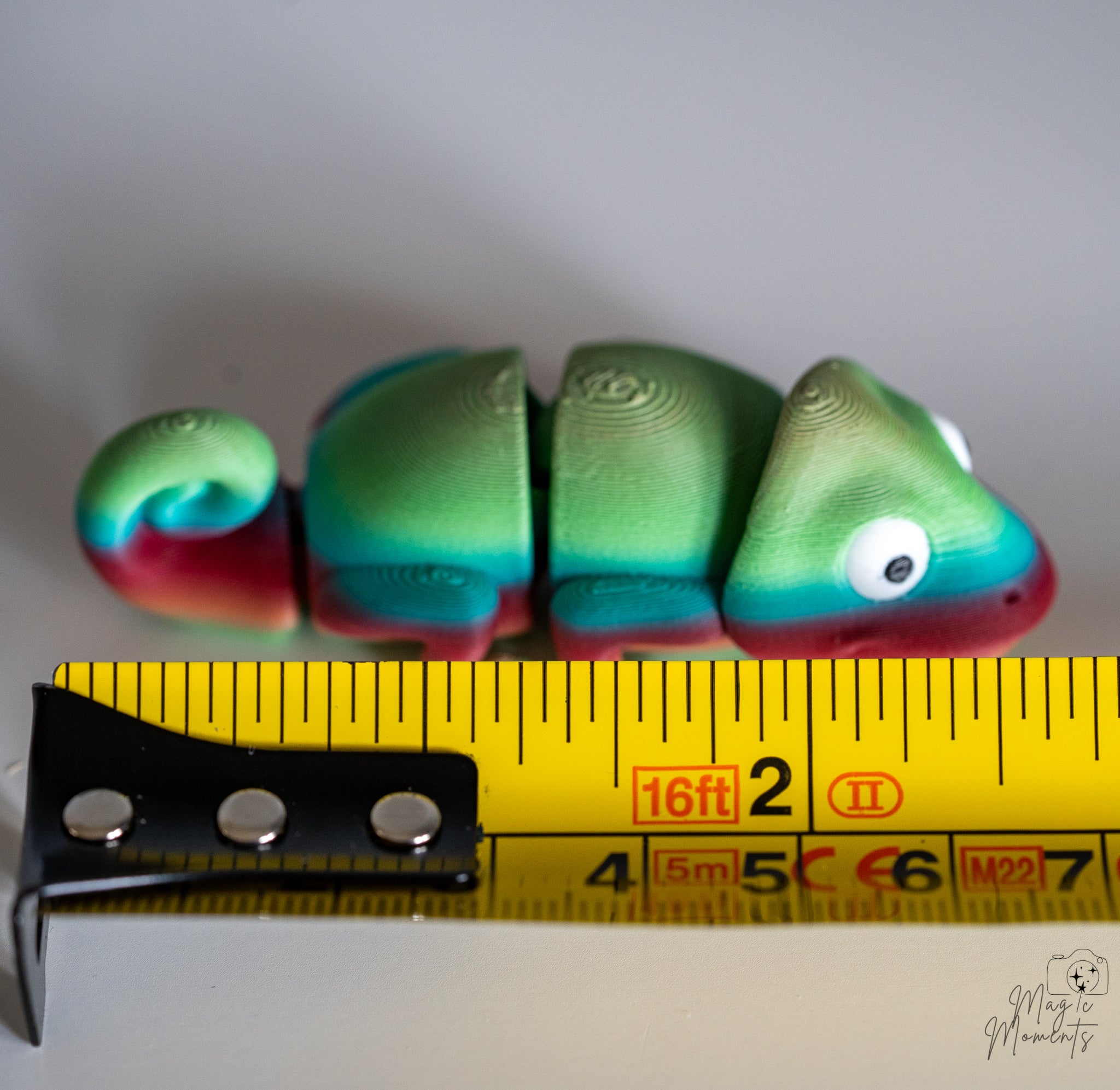 chameleon figurine next to measuring tape for scale