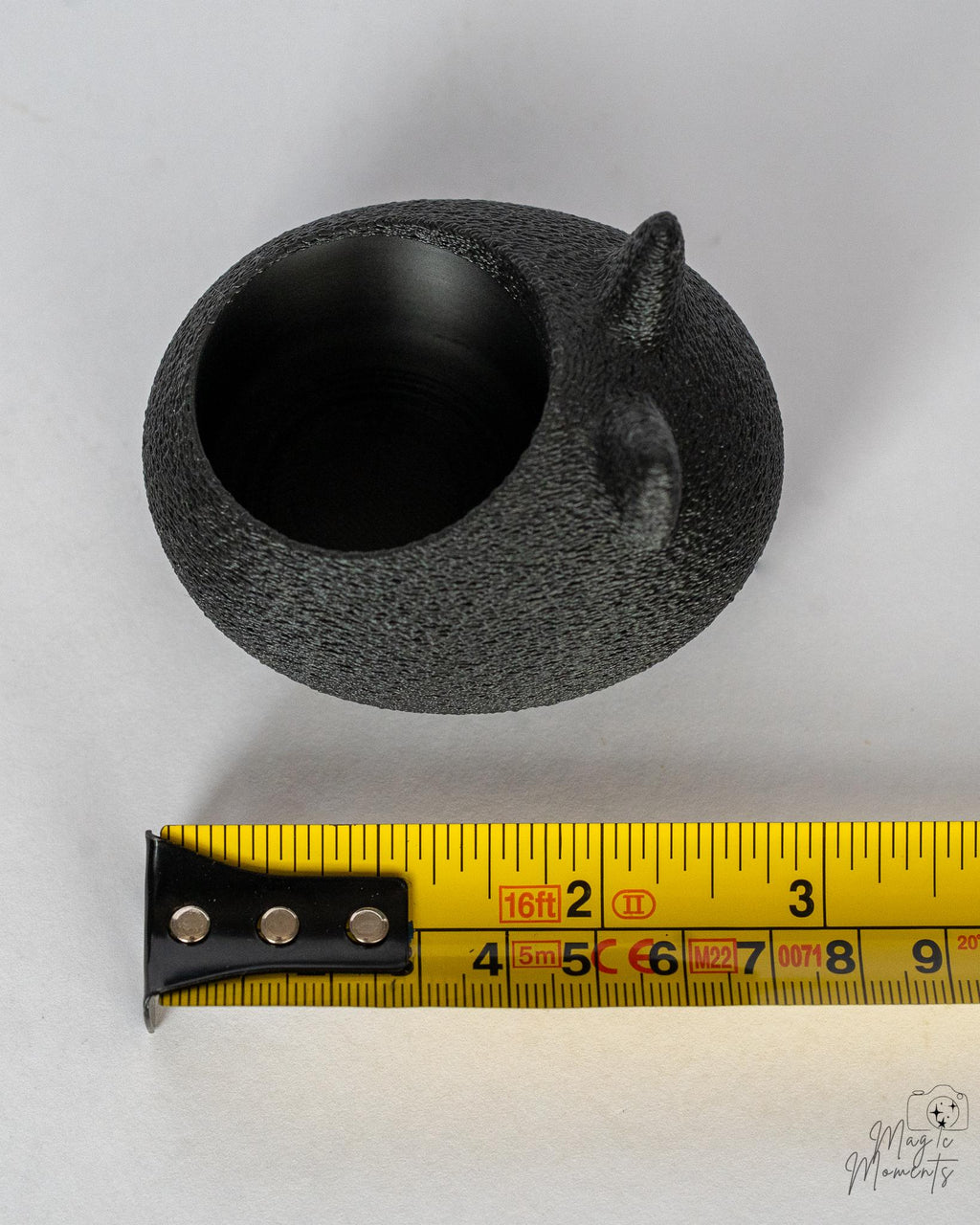 black cat tealight holder next to measuring tape for scale