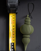 green modern ribbed christmas bauble next to measuring tape for scale