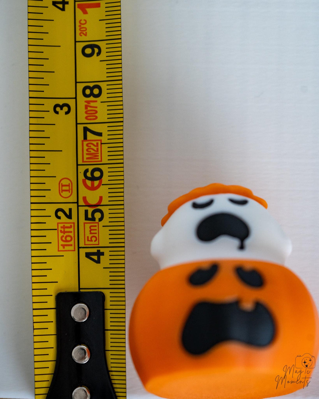 Ghost pumpkin clicker next to measuring tape for scale