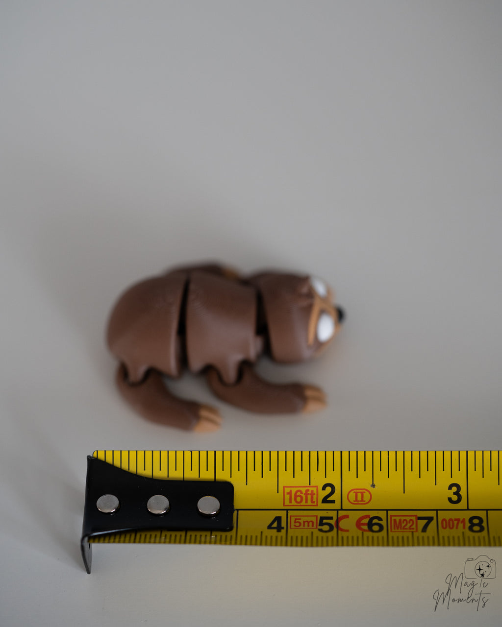 sloth figurine next to measuring tape for scale