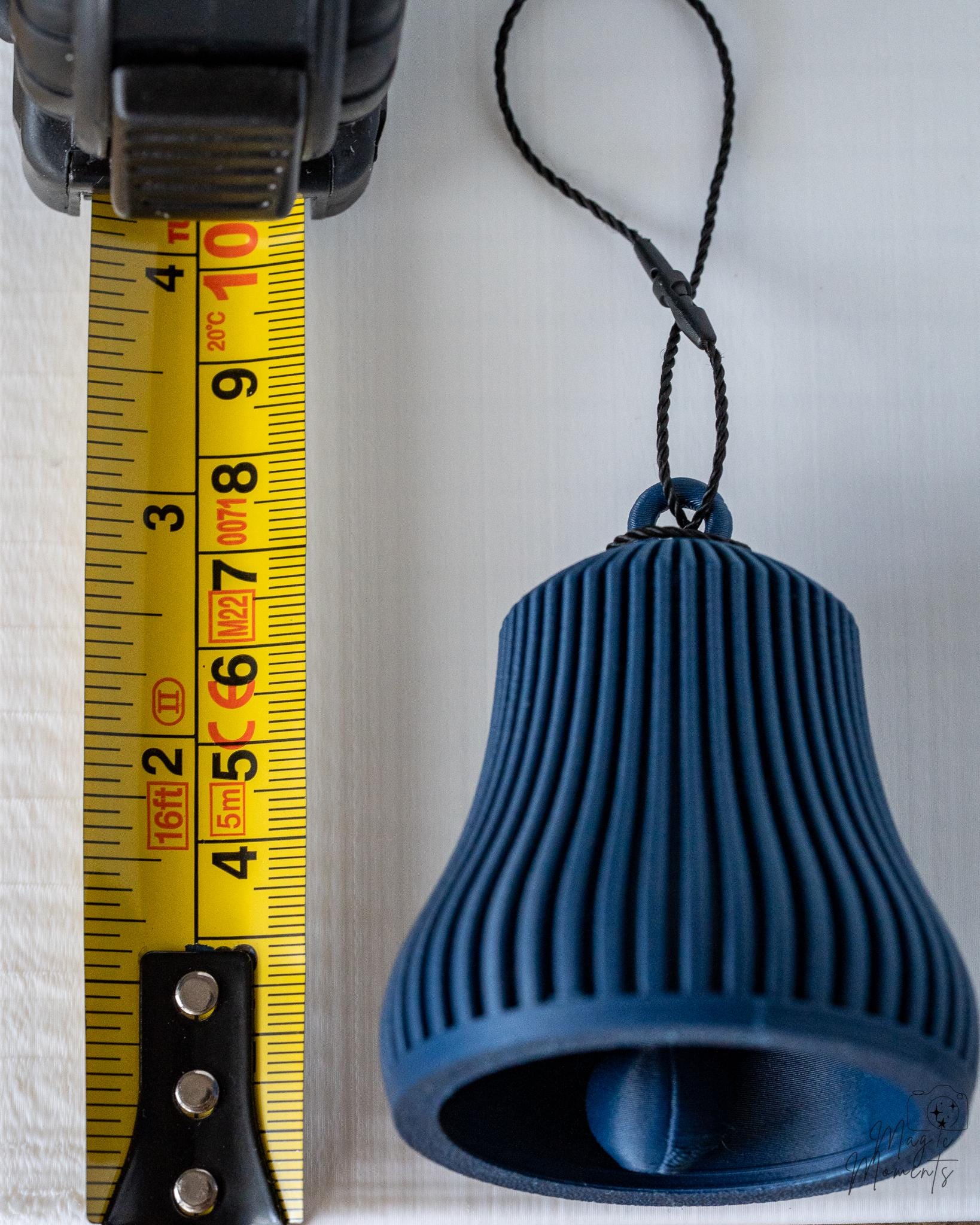 blue christmas bell ornament next to measuring tape for scale