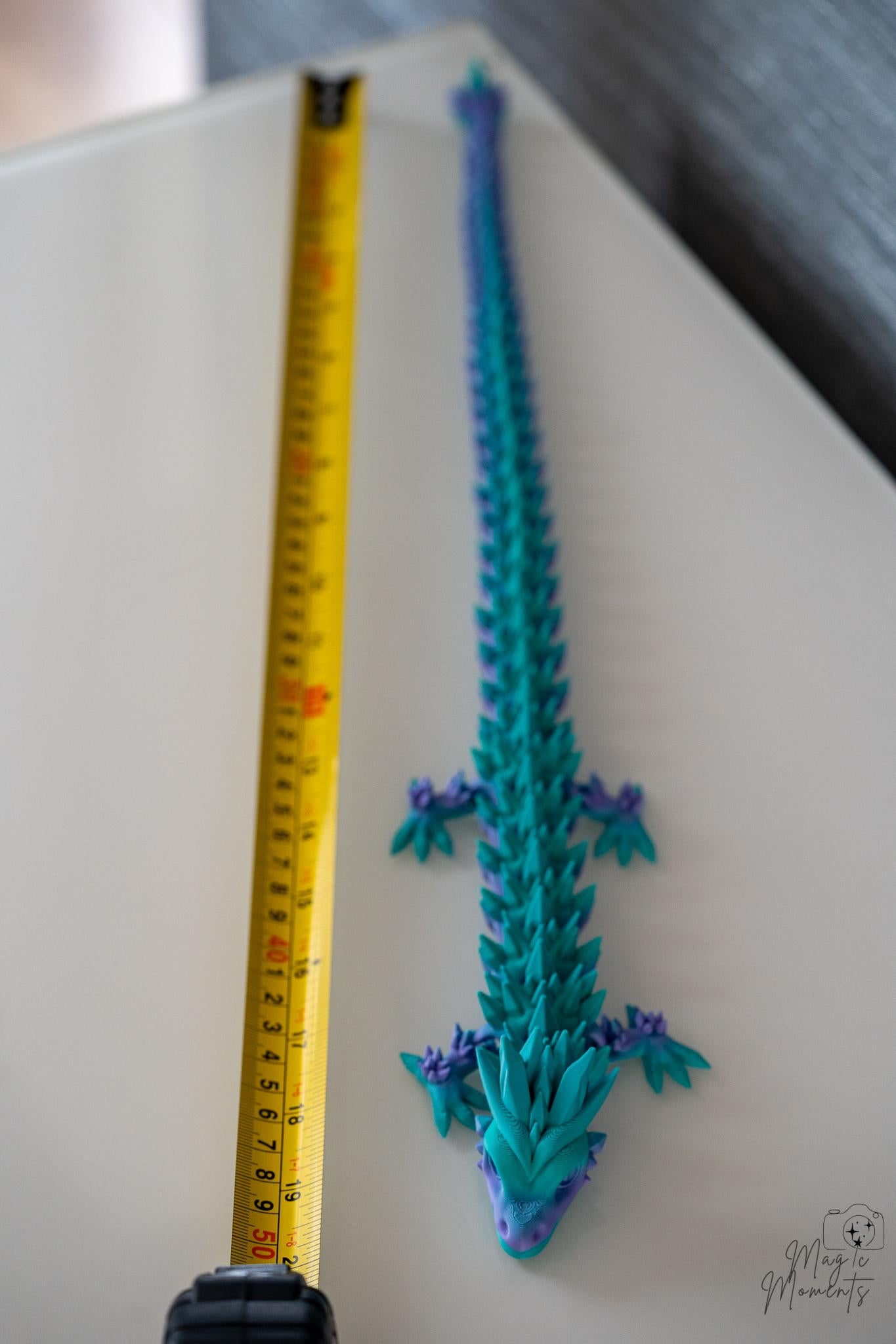 articulated dragon next to measuring tape for scale