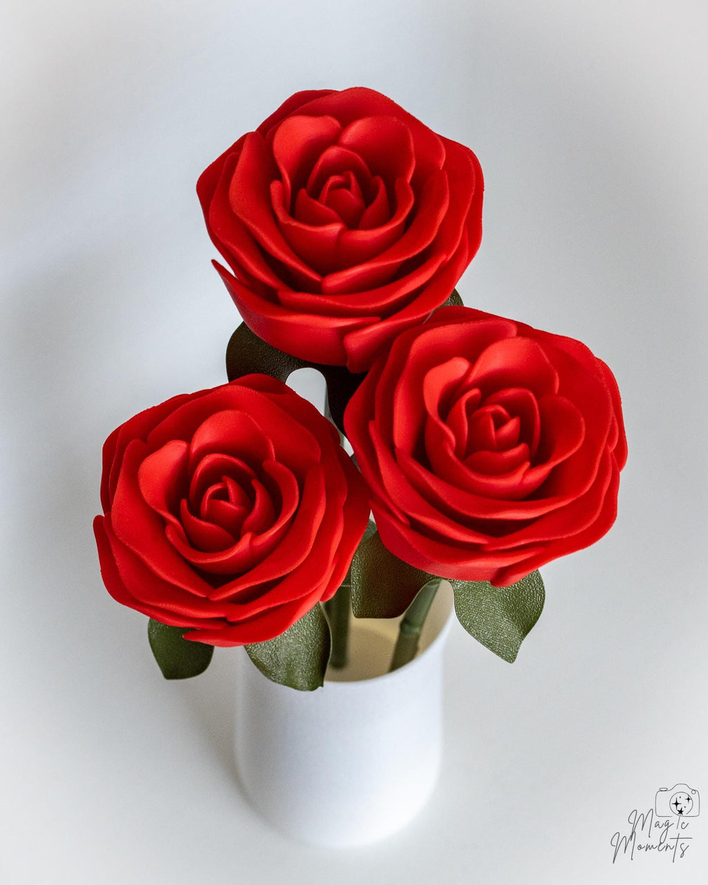 Three red roses in a white vase on a white background