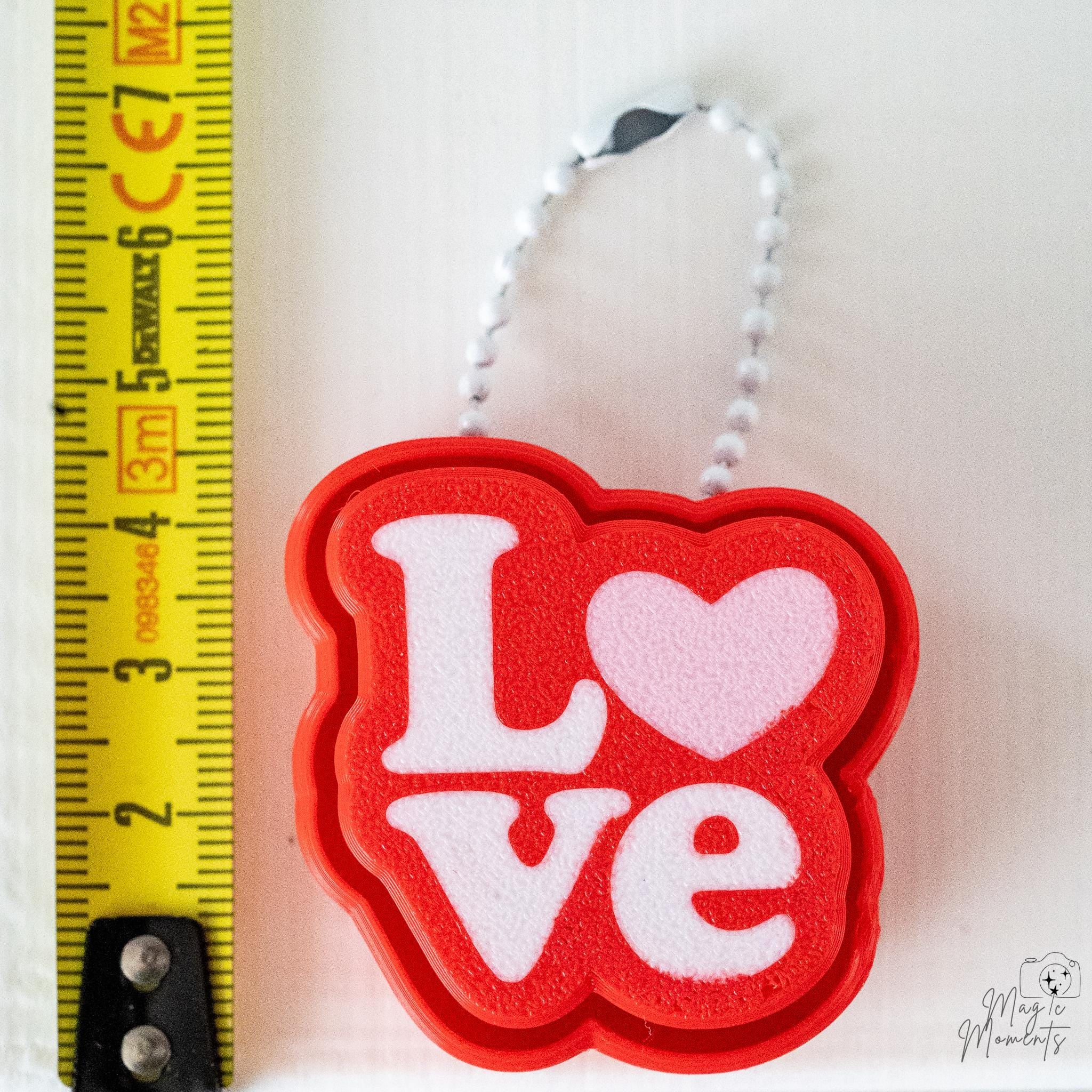 Love clicker keychain next to measuring tape for scale
