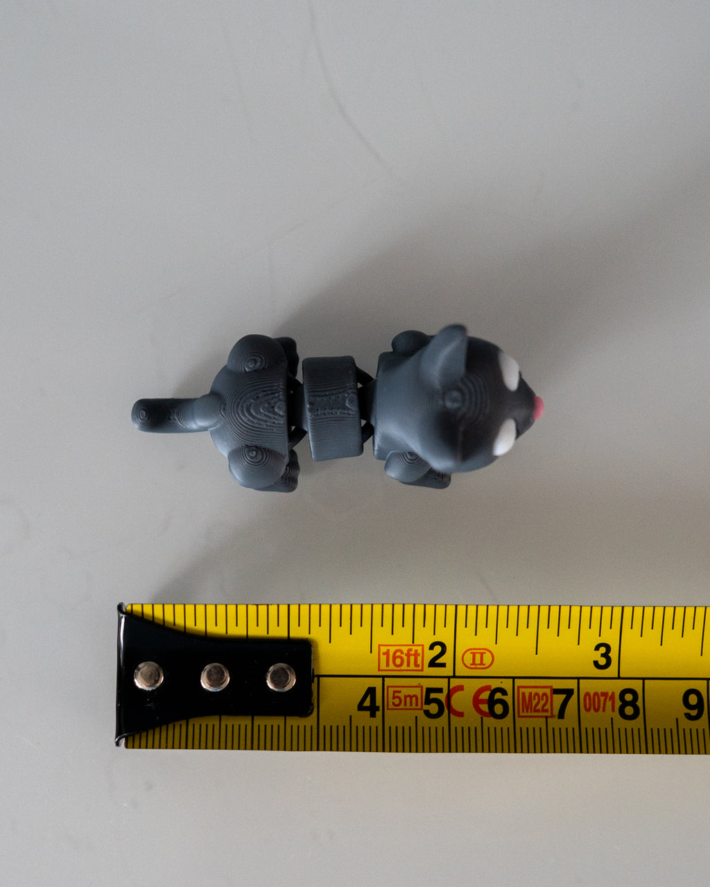 grey cat figure next to measuring tape for scale