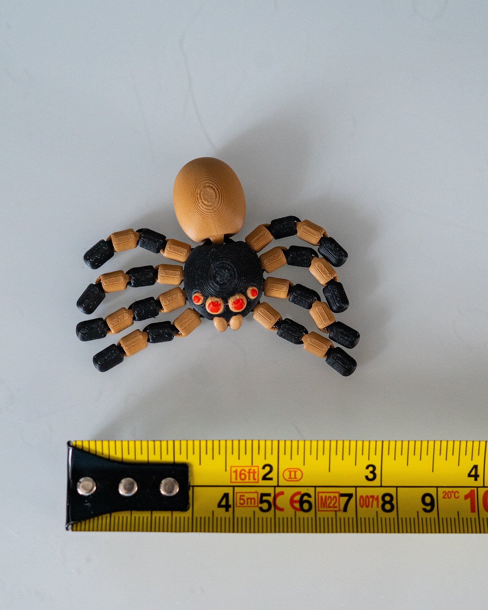 spider figurine next to a yellow measuring tape for a scale