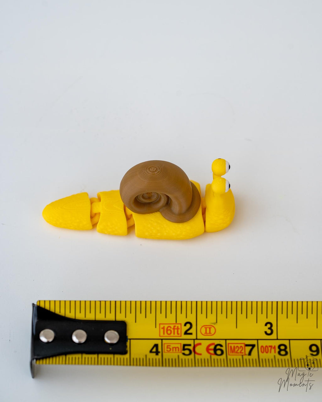 snail figurine next to measuring tape for scale