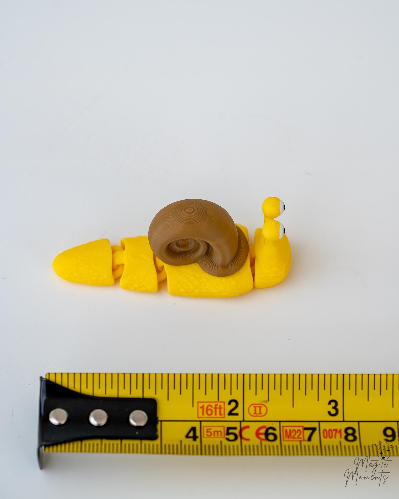 snail figurine next to measuring tape for scale