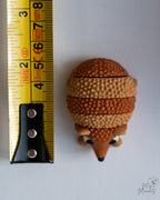 hedgehog figurine next to measuring tape for scale