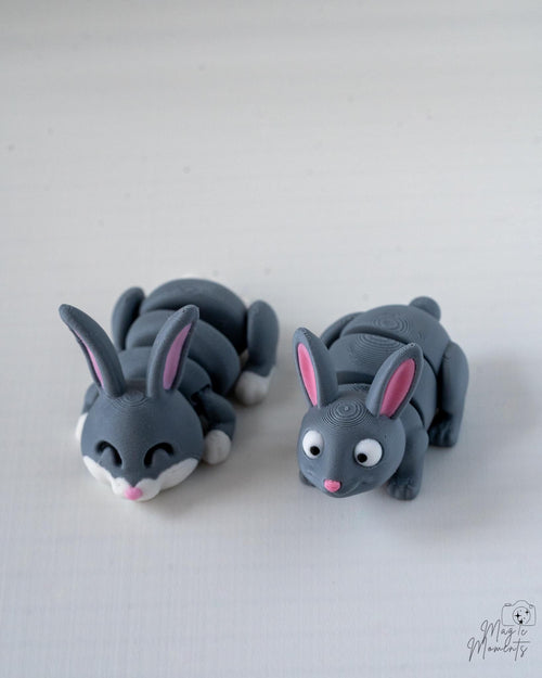 Two gray rabbit/bunny figurines on a light gray background
