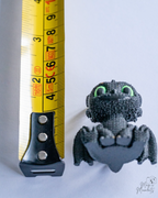 Mini dragon figure inspired by Night Fury design next to a measuring tape for a scale