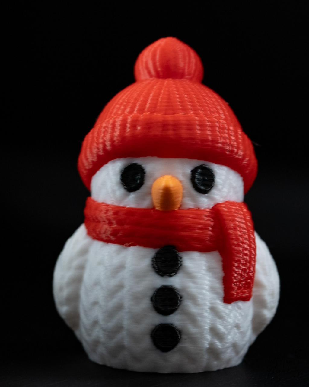 Snowman figurine with a red hat and scarf on a black background