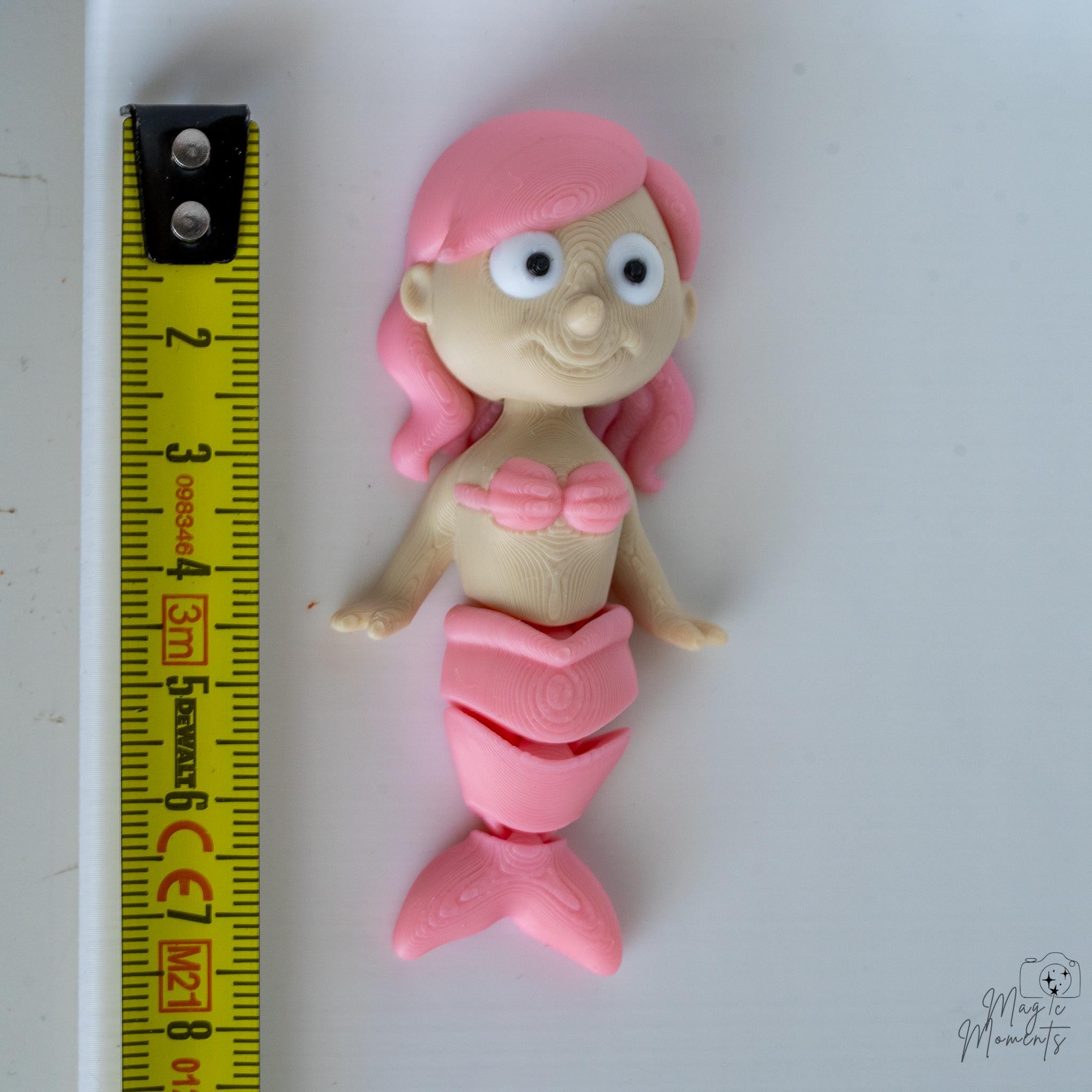 pink mermaid figurine next to measuring tape for scale
