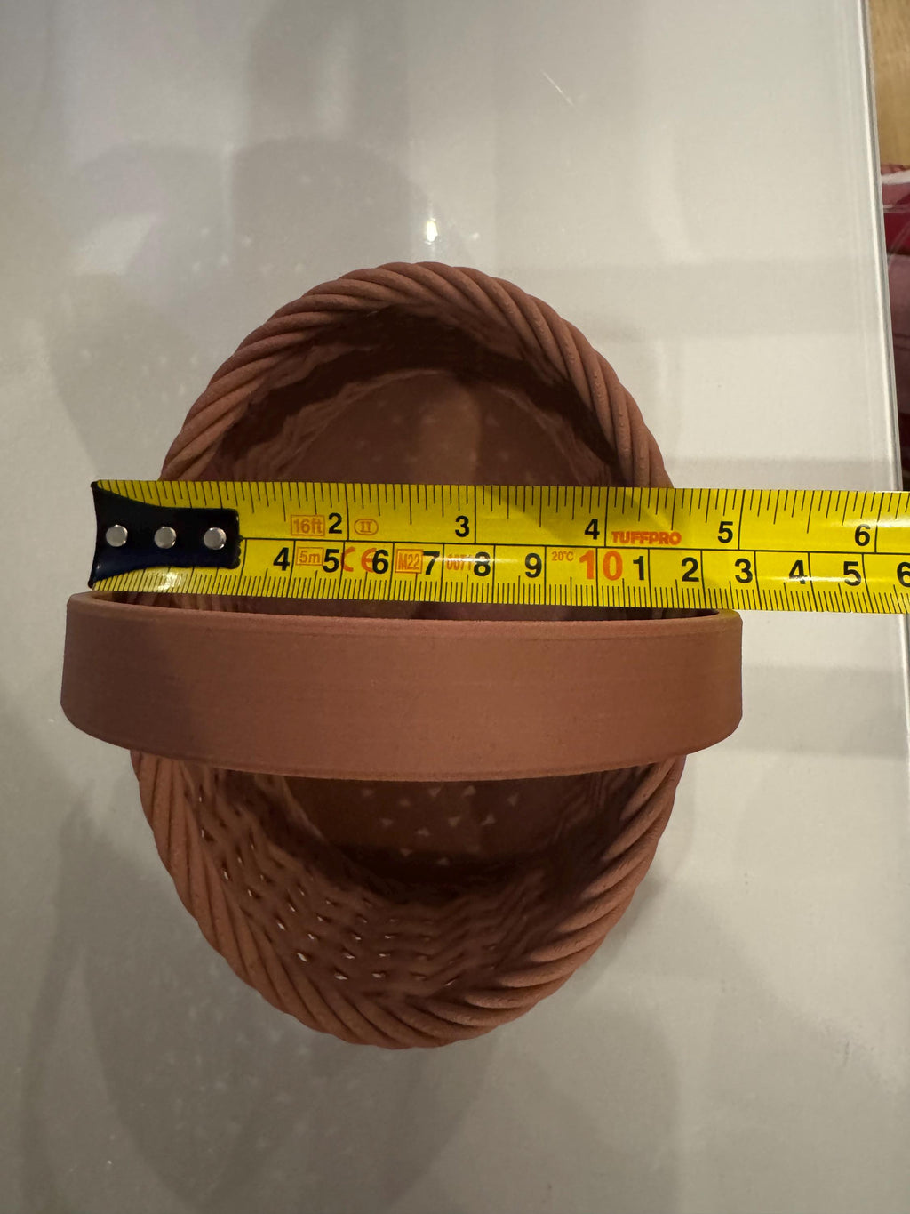 brown woven basket side view next to measuring tape for scale