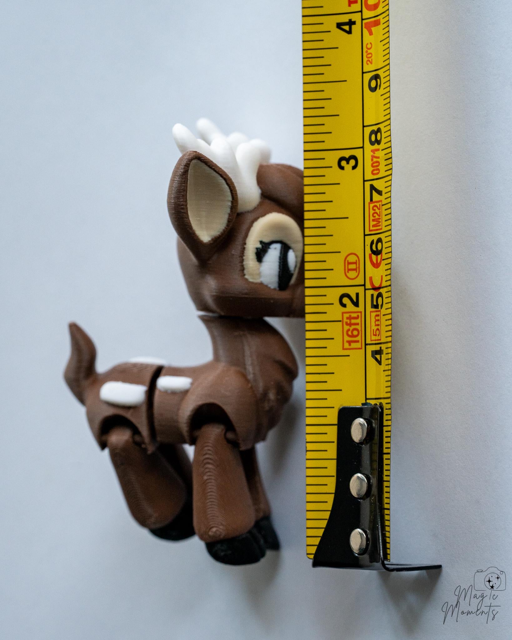 Small brown deer figurine next to a measuring tape for scale
