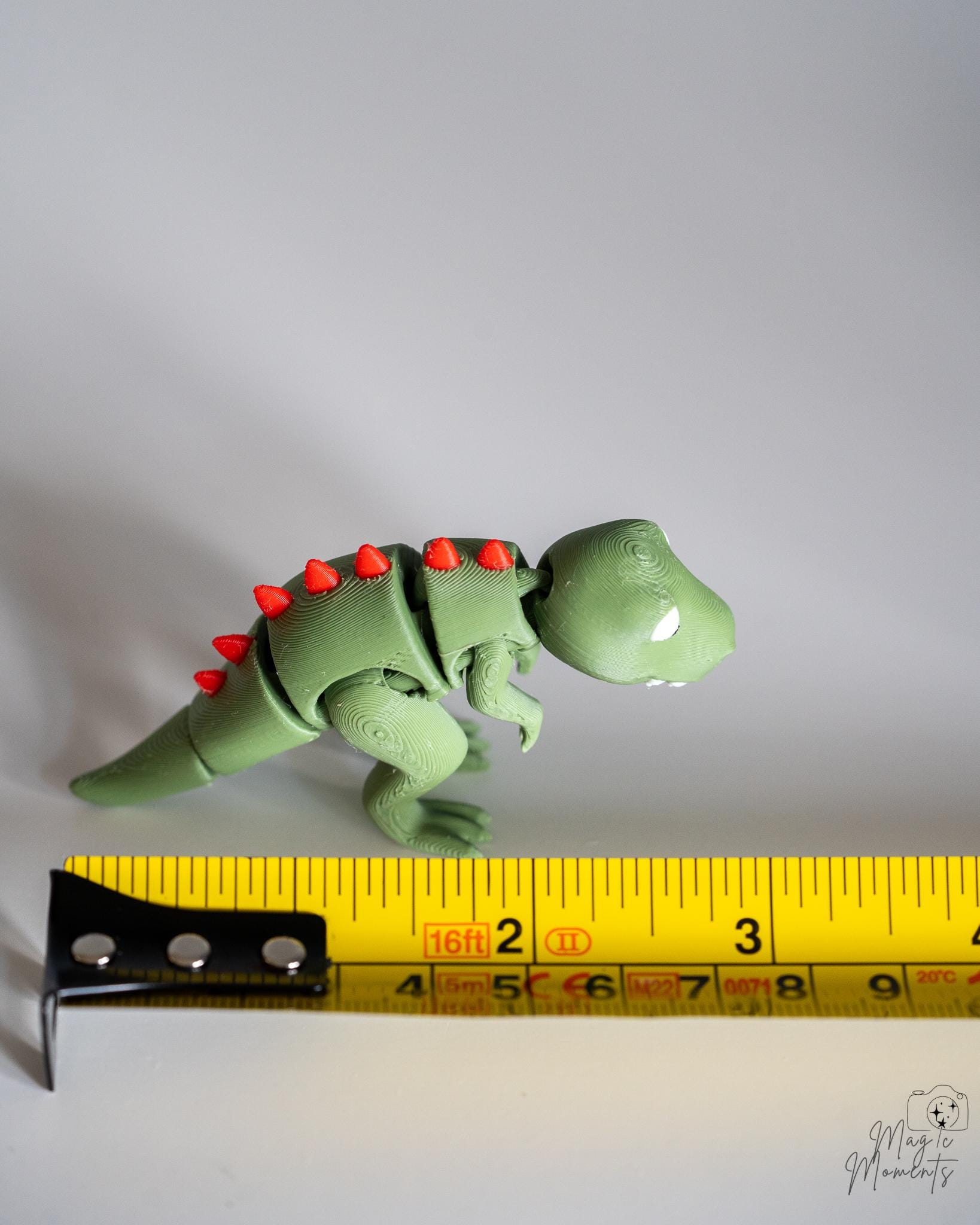 green t rex figure next to measuring tape for scale