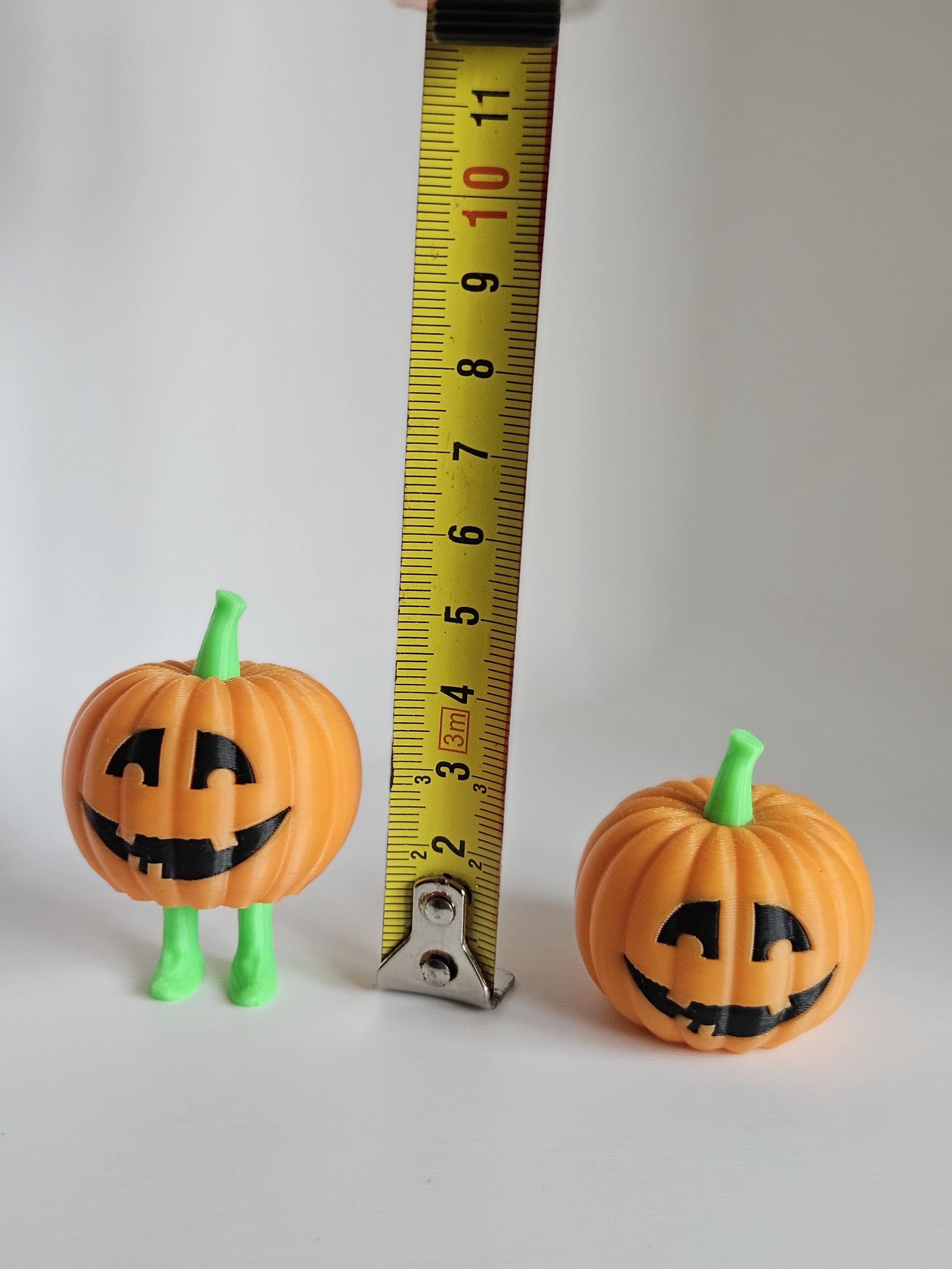 Mini Halloween pumpkins next to measuring tape for scale