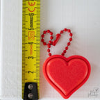 red heart clicker next to measuring tape for scale